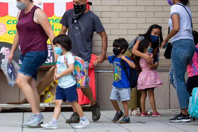 A group of parents and kids, all in masks, walk on the sidewalk outside PS 133 in Brooklyn.